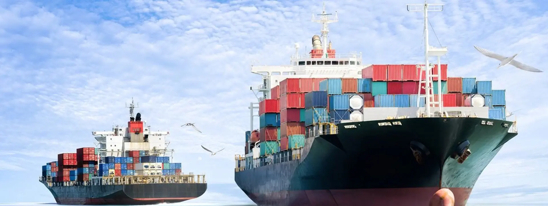 A large cargo ship with two smaller ships in the background.